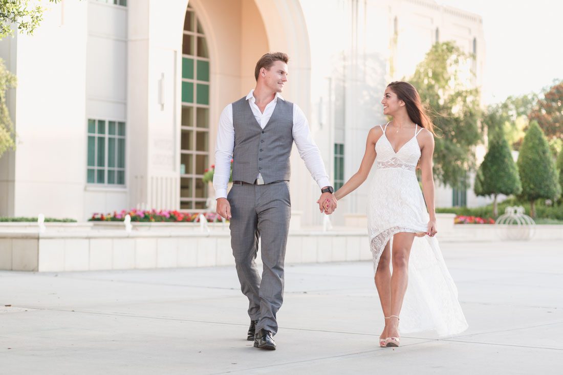 Gorgeous couple walking in front of City Hall in historic Winter Garden during their engagement photography shoot with top Orlando wedding photographer and videographer