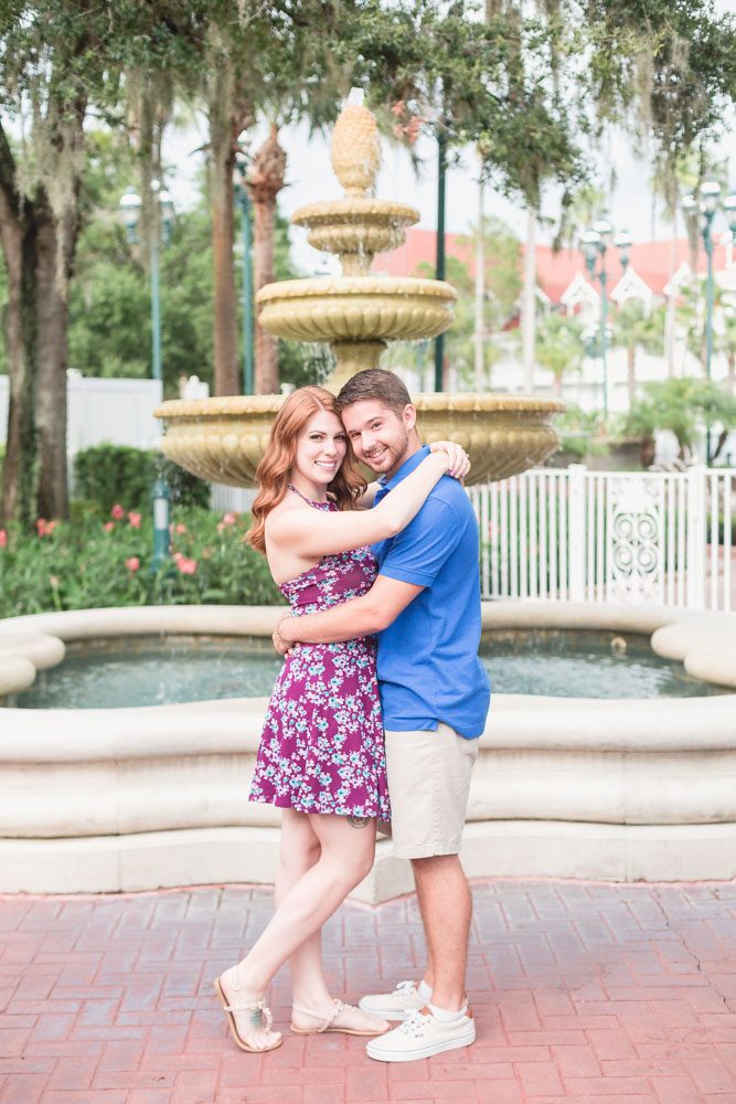 Newly engaged couple poses in front of a fountain at Disney's Grand Floridian Resort during their Orlando engagement photography session