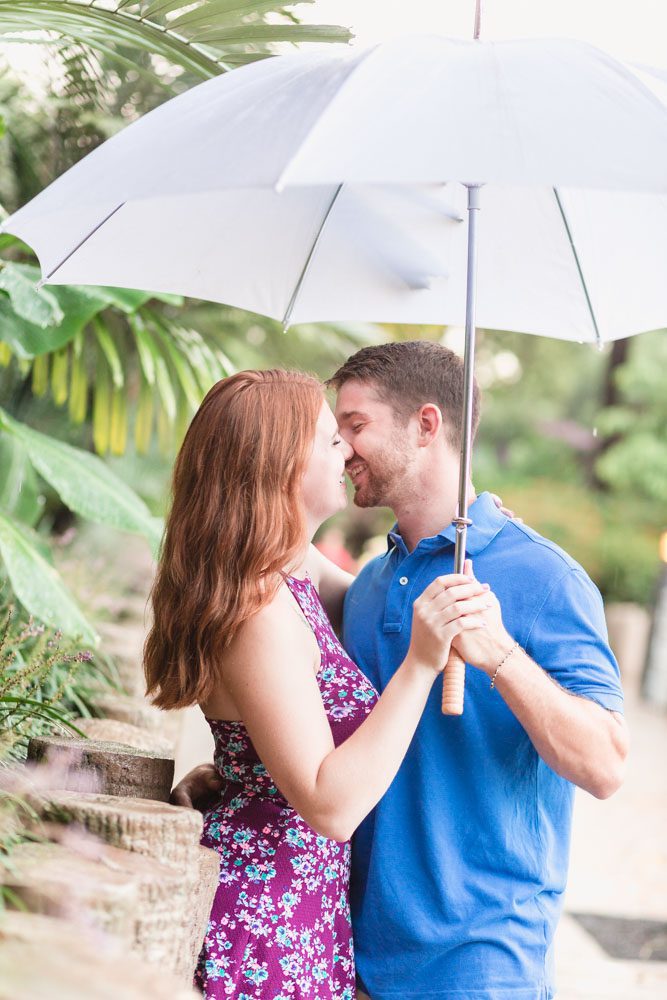 Rainy day engagement photography shoot at Disney resort with a couple cuddling under an umbrella captured by top Orlando engagement and proposal photographer