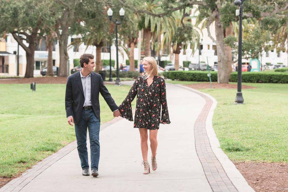 Newly engaged couple walks along the sidewalk at Lake Eola in downtown Orlando after their surprise proposal is captured by top Orlando photographer