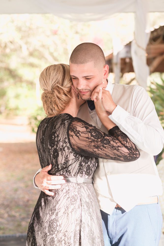 Groom shares an emotional first dance with his mom during their outdoor wedding reception in a backyard in Kissimmee