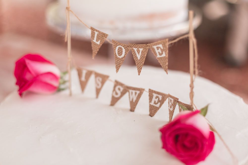 Adorable cake topper that reads 'love is sweet' in burlap fabric for a rustic chic DIY wedding in Kissimmee