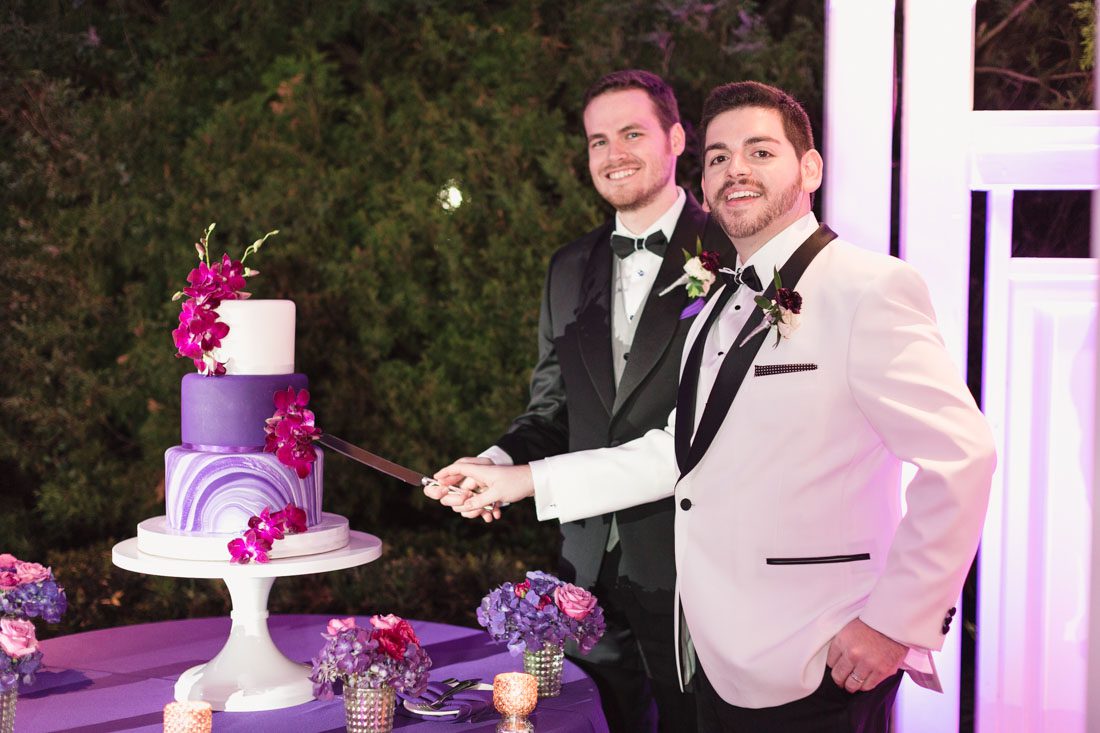 Photo of Grooms cutting the cake at their Orlando gay wedding at Cypress Grove outdoor venue