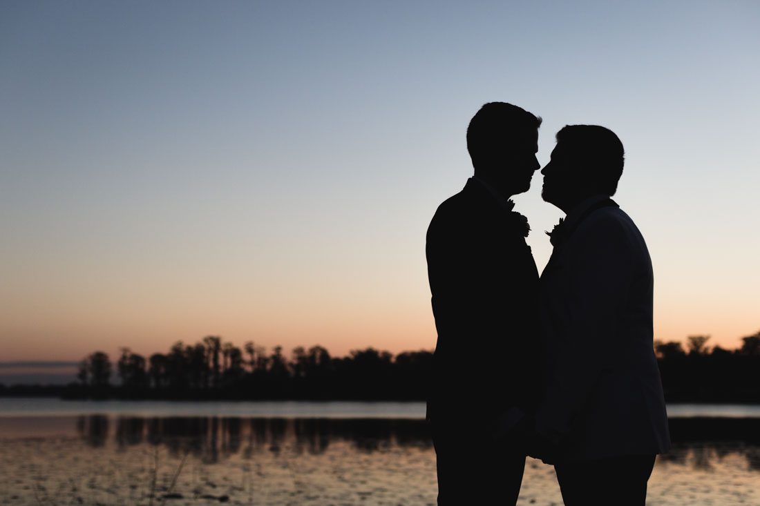 Silhouette photo of two grooms during their gay wedding in Orlando at Cypress Grove on the lake