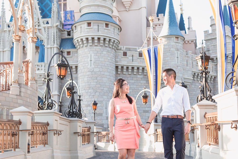 Engaged couple walking along Cinderella's castle at Walt Disney World park in Magic Kingdom during their engagement photography session in Orlando