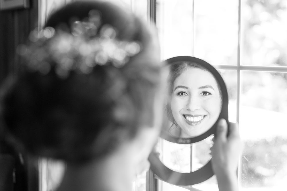Bride looking at herself in the mirror during her wedding at the Estate on the Halifax east of Orlando, Florida