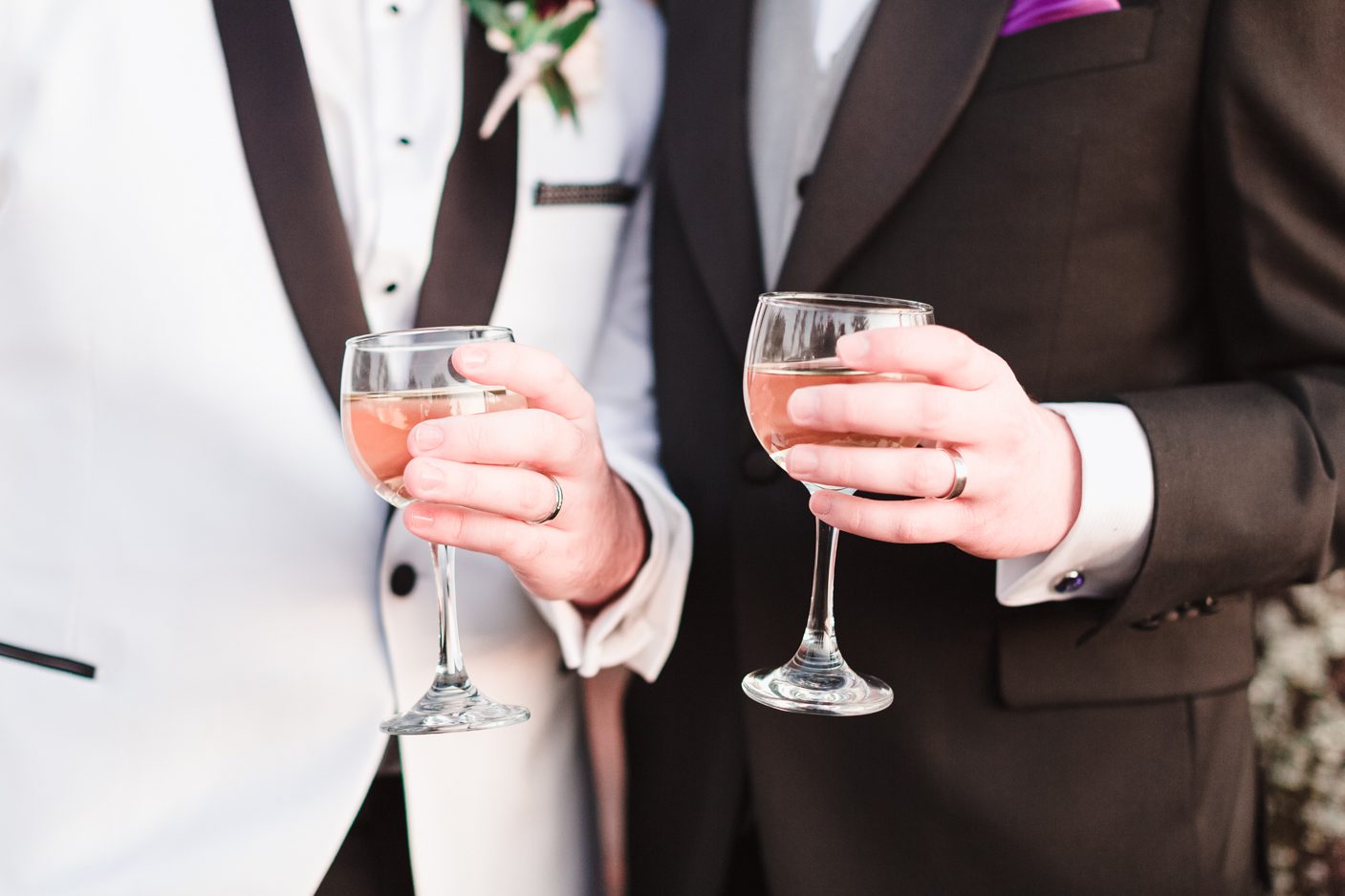 Photo of two grooms holding cocktails and showing their wedding bands during their gay wedding in Orlando