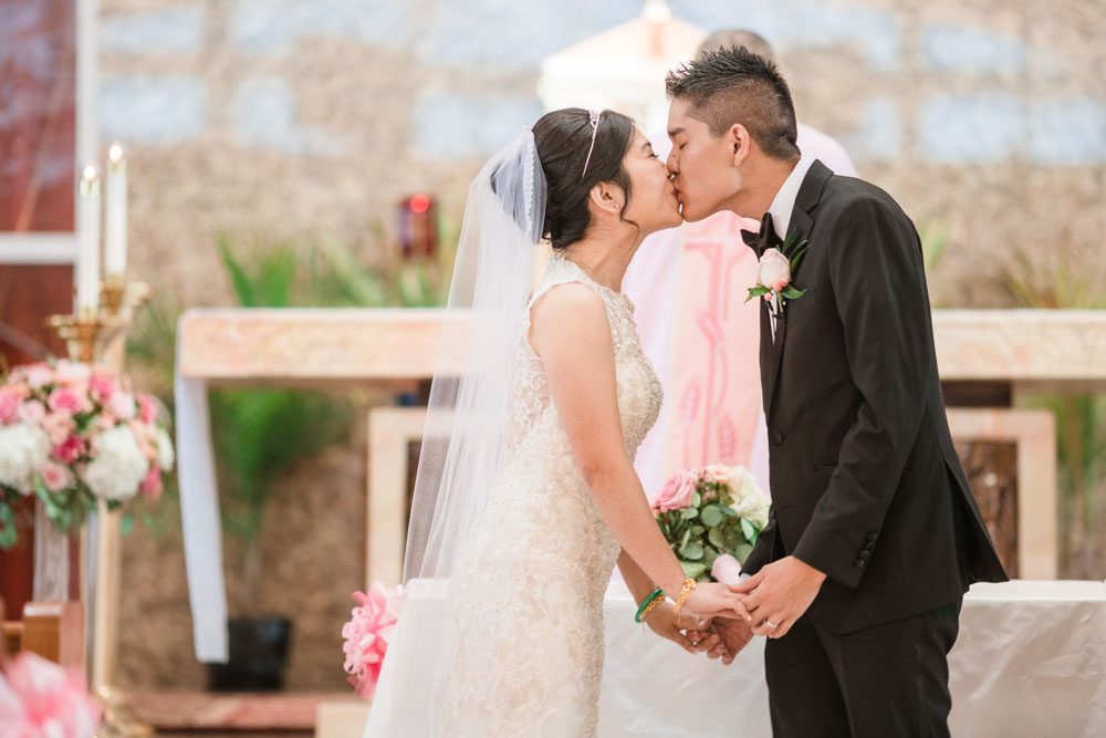 Asian bride and groom share their first kiss during their Catholic wedding ceremony in Oklahoma City