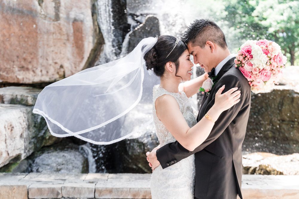 Candid portrait of the bride and groom at Myriad Gardens in front of a waterfall in Oklahoma City captured by traveling photographers from Orlando
