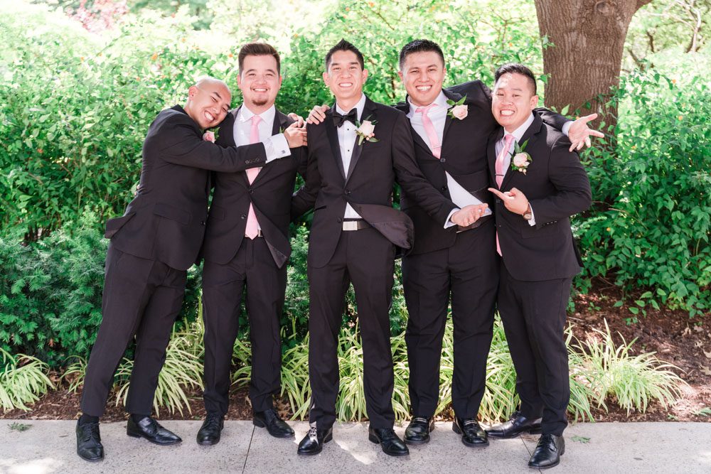 Groom and groomsmen wearing black tuxes with pink ties at Myriad Gardens in Oklahoma City
