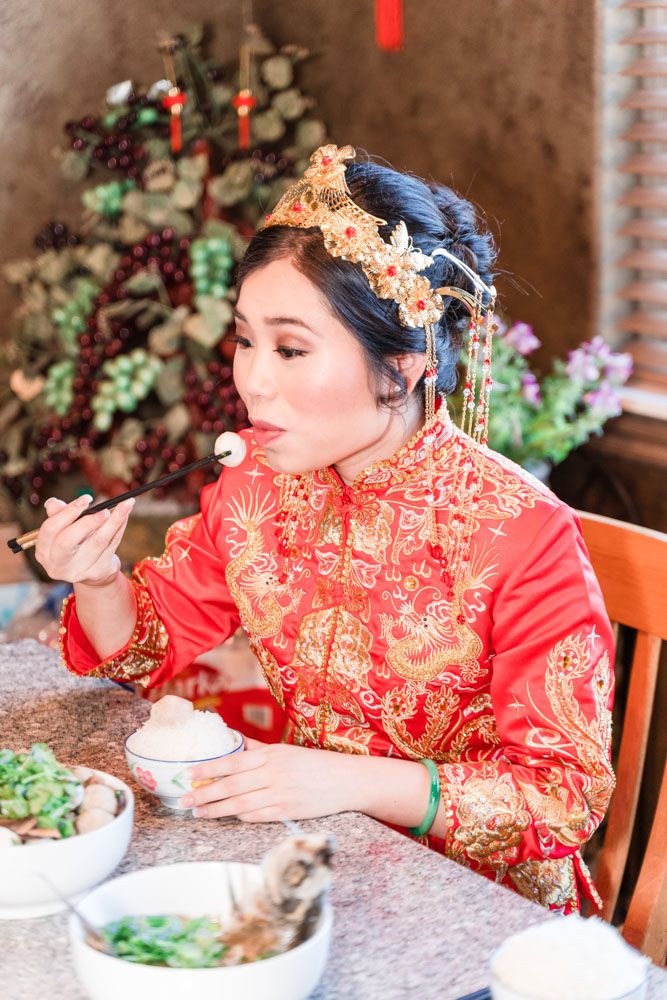 Chinese bride eats her traditional breakfast with chopsticks during her Asian wedding in Oklahoma City captured by Orlando wedding photographer