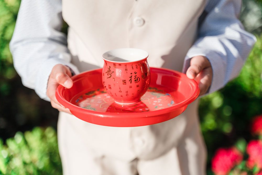Boy serving tea for a chinese and vietnamese tea ceremony at a wedding in Oklahoma City captured by top Orlando wedding photographers